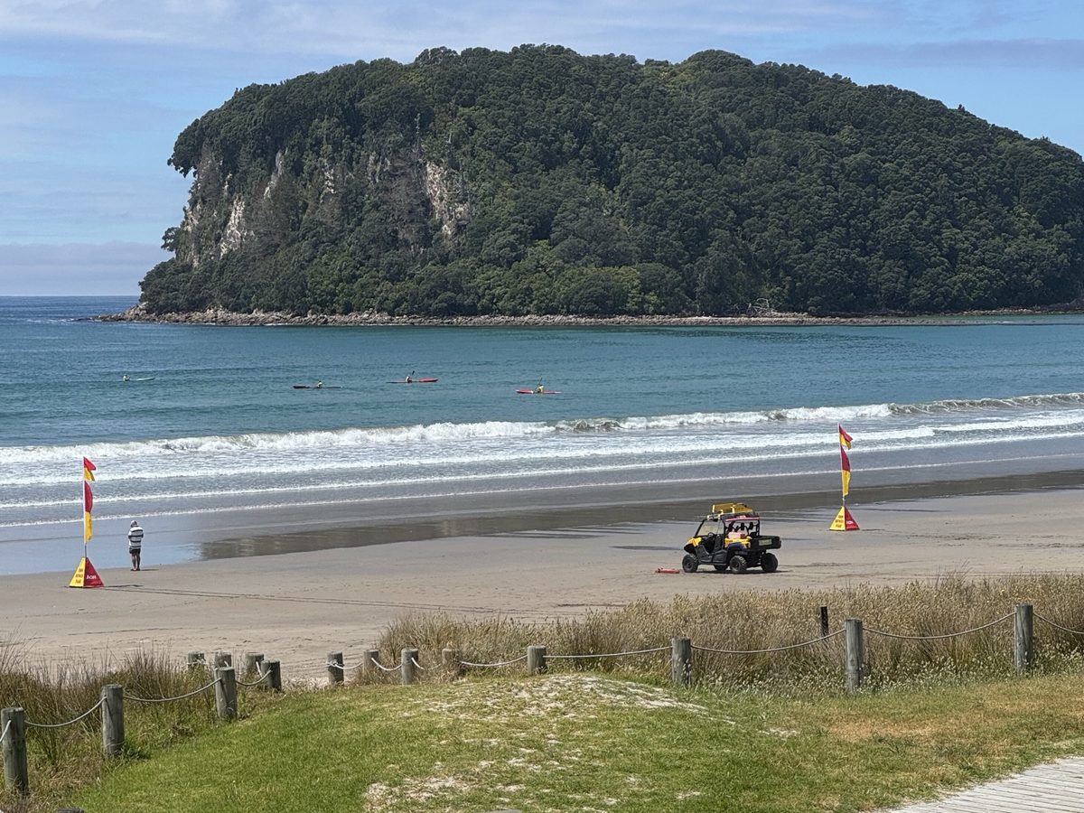 A surf rescue buggy with a rescue board on the dunes, the beach and headland behind